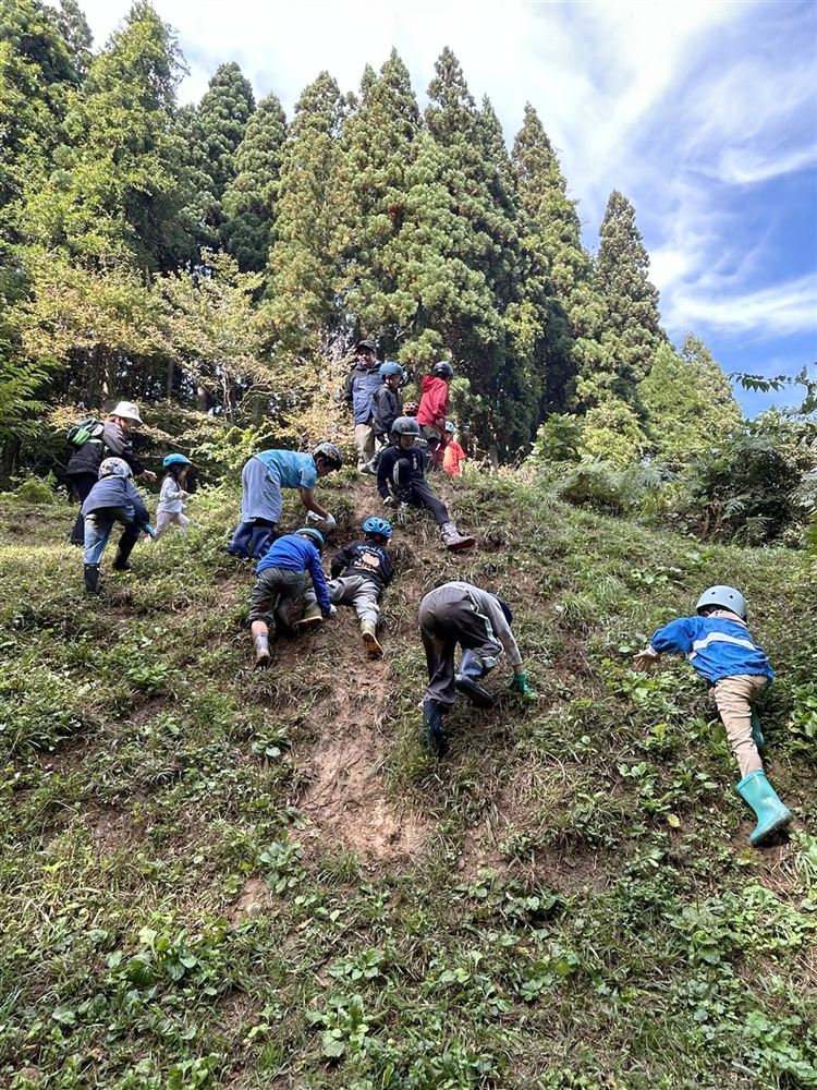森の斜面を登る子どもたち